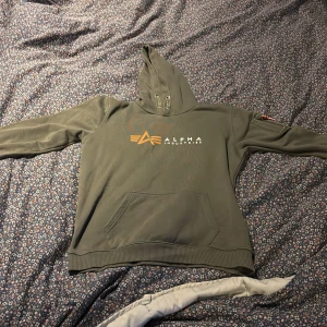Grön hoodie från Alpha Industries - Säljer en grön hoodie från Alpha Industries med en logga på bröstet. 