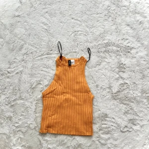 Orange ribbad linnetopp - Snygg orange ribbad linnetopp med smala axelband. Perfekt för varma dagar och kan enkelt matchas med olika outfits.