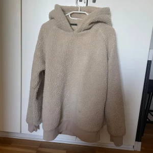 Beige fleece hoodie - Mysig beige hoodie i fleece-material med huva. Perfekt för kyliga dagar när du vill hålla dig varm och bekväm. Den har långa ärmar och en avslappnad passform.