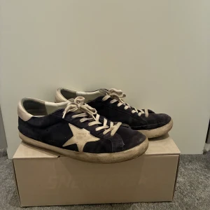 Marinblå sneakers med stjärndetalj - Snygga marinblå sneakers från Golden Goose med en vit stjärna på sidan. Skorna har snörning och en rund tå. Perfekta för en avslappnad stil med en touch av unik design.
