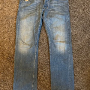 Diesel jeans - Säljer ett par klassiska blå jeans från Diesel, modell Larkee. De har en rak passform och normal midja. Jeansen har en snygg tvätt med lätt slitna detaljer och fem fickor. Perfekta för en avslappnad stil.