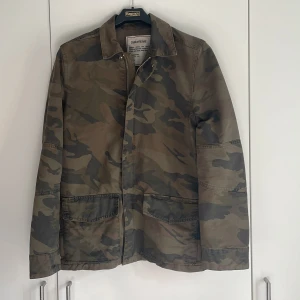 Camouflagejacka från Zadig & Voltaire - Snygg camouflagejacka från Zadig & Voltaire med klassisk krage och dragkedja framtill. Jackan har två stora fickor och är perfekt för en avslappnad stil. Jackan är ganska tunn så passar perfekt till våren och sommar kvällarna. Storlek s. Bara att höra Av dig vid frågor. 