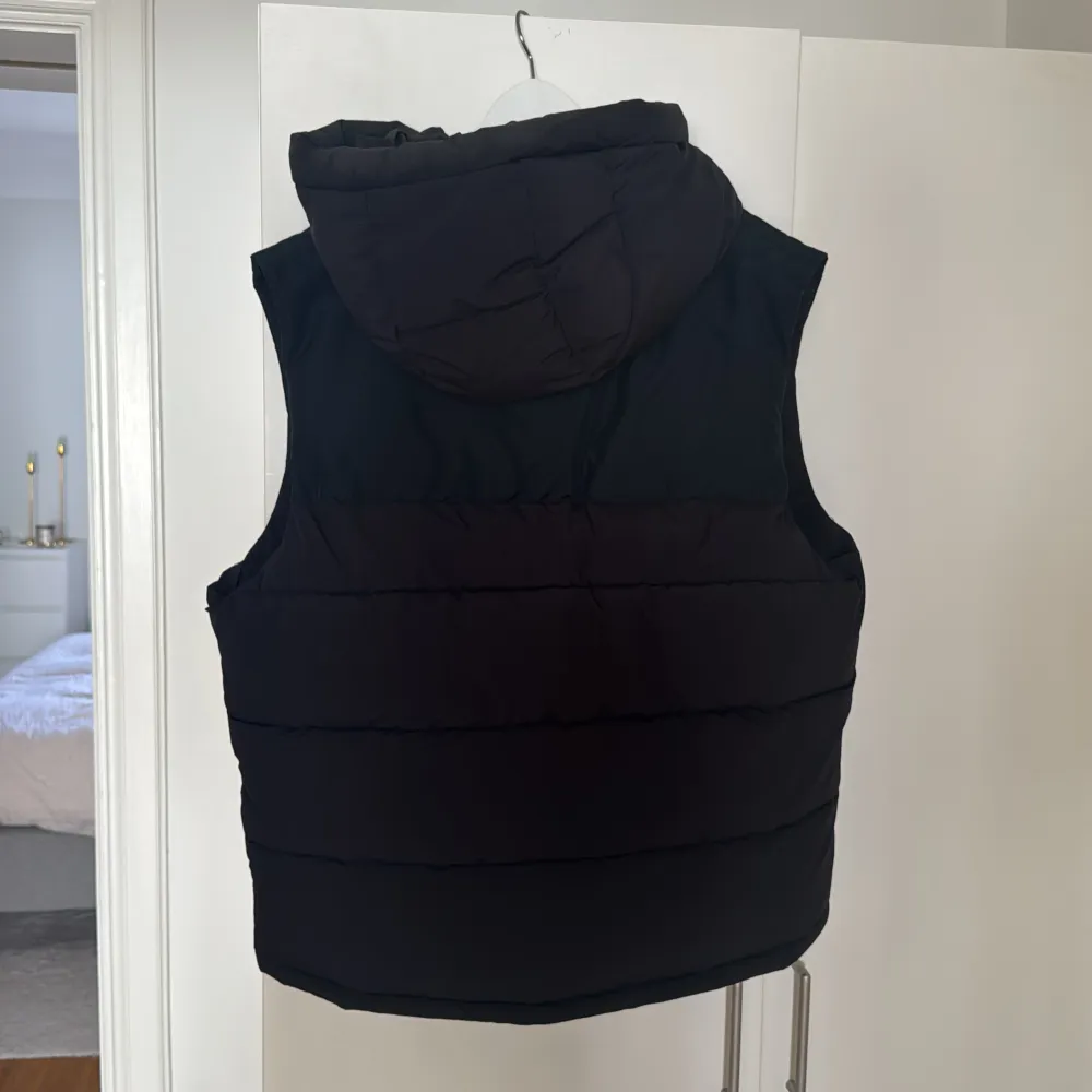 Säljer en svart dunväst från Zara med dragkedja och huva. Västen har en stilren design med två praktiska fickor framtill. Perfekt för kyligare dagar.. Takit.
