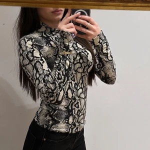 Ormmönstrad tröja från Gina Tricot - Ormmönstrad tröja från Gina Tricot i svart och beige. Tröjan har en tight passform och långa ärmar, i storlek s