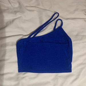 Blå oneshoulder topp - Snygg blå oneshoulder topp med dubbla axelband. Passar bra till både jeans och kjol.