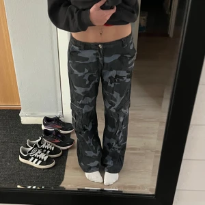 Lågmidjade baggy cargobyxor - Säljer ett par coola camouflage cargobyxor i marinblått. Byxorna har flera praktiska fickor och en baggy passform. Säljer då jag har bytt stil. Jag är 171cm lång