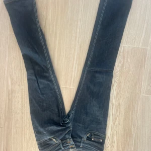 Mörkblå low rise jeans med broderad detalj - Snygga mörkblå jeans med broderad detalj på bakfickan. De har en klassisk femficksdesign och en bekväm passform. Perfekta för en avslappnad stil.