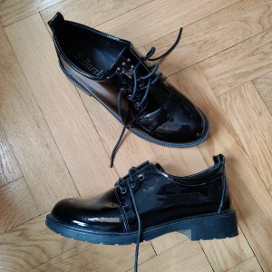 Svarta skor med bi-detalj - Unika svarta lackskor med snörning och unika detaljer. Endast använda en gång så skicket är i topp! 