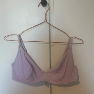 Ljuslila bh-topp - Säljer en ljuslila bikinitopp med justerbara axelband och bygel för extra stöd. Toppen har en enkel design och är tillverkad i ett mjukt material för bekväm passform. 