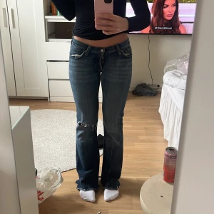 Blå bootcut jeans - Säljer ett par blå bootcut jeans med slitna detaljer vid knäna. Jag är 167cm!