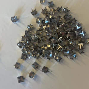 Silvriga nitar i pyramidform - Säljer ett gäng silvriga nitar i pyramidform som passar perfekt för att dekorera skor, väskor eller kläder. Nitarna har 4 piggar på baksidan för enkel fastsättning i material som tyg eller läder. Ger en cool och edgy look till dina accessoarer. Passar perfekt för er som har valentino skor nitarna är exakt samma storlek som originalet 5 mm, 35 kr styck!!