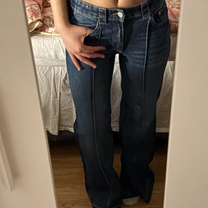 Blå bootcut jeans - Säljer ett par klassiska blå bootcut jeans med normal passform och låg midja. Jeansen har fem fickor, knapp och dragkedja framtill samt tydliga sömmar. Perfekta för en avslappnad och tidlös look.
