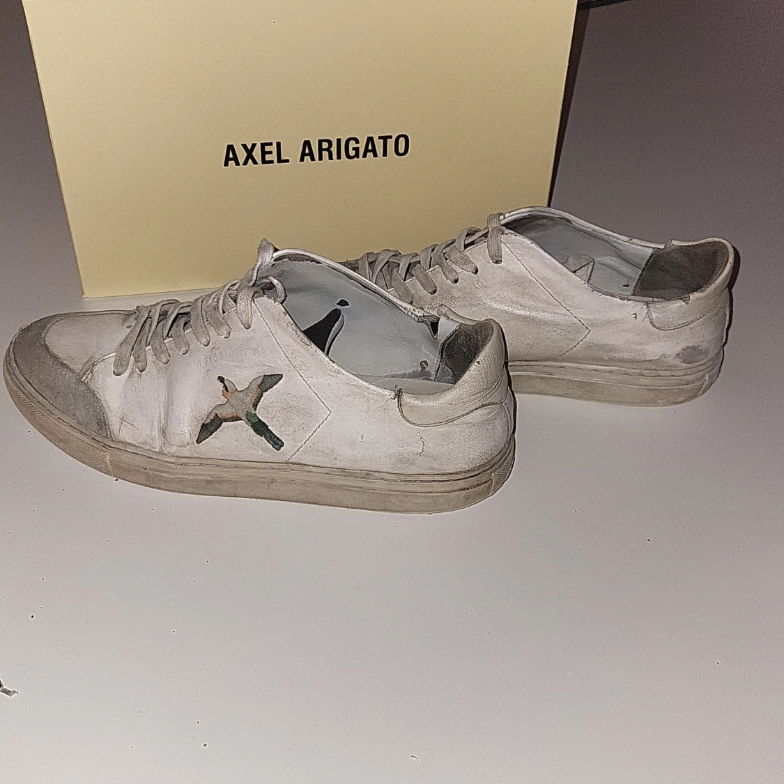 Vita sneakers från Axel Arigato med broderad fågel