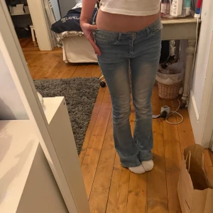 Lågmidjade, ljusblå bootcut jeans med broderad bakficka - Säljer ett par lågmidjade ljusblå jeans med bootcut passform och låg midja. Jeansen har en snygg broderad detalj på bakfickan. Perfekta för dig som gillar en avslappnad och trendig stil.