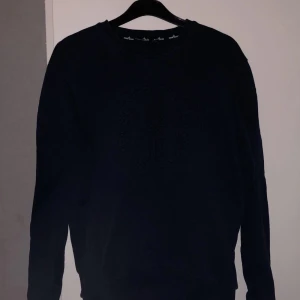 Svart sweatshirt från Stone Island - Säljer en mörkblå sweatshirt från Stone Island med stort broderat logotypmärke på bröstet. Säljer den för 300kr då den är använd och inte kommer till användning men är ändå i bra skick:)