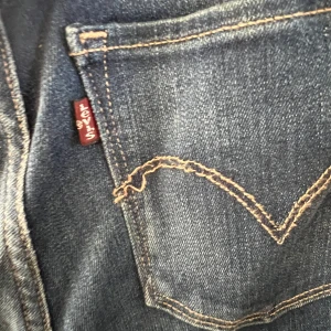 Levi's High Rise Skinny Jeans - Mörkblå skinny jeans från Levi's med hög midja och klassiska bakfickor med gul söm. Modellen är tight och har en stilren look som passar till många olika outfits.