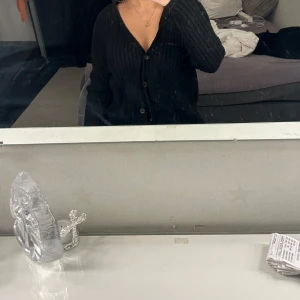 Svart ribbad kofta - Säljer en svart ribbad kofta med knappar framtill. Koftan har lång ärm och en klassisk v-ringning. Perfekt att slänga över en topp eller bära som den är.