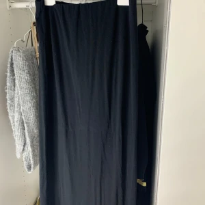 Svart långkjol från 157 - Enkel och stilren svart långkjol från 157. Kjolen har rak passform och är gjord i ett mjukt material med resår i midjan. Perfekt att matcha med en stickad tröja eller en enkel topp.