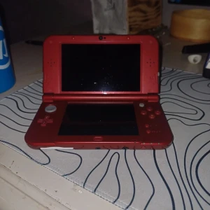 Röd Nintendo 3DS XL Monster Hunter Generations Edition + Mario Party: Star Rush - Säljer en röd Nintendo 3DS XL Monster Hunter Generations Edition med svart Monster Hunter-motiv på ovansidan. Konsolen har dubbla skärmar, styrkors, knappar och medföljer en stylus. Spelet Mario Party: Star Rush till Nintendo 3DS ingår.