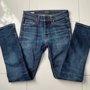 Blå slim fit jeans från Jack & Jones - Snygga blå jeans från Jack & Jones med en slim passform. De har en klassisk femficksdesign och är tillverkade i slitstarkt denim. Perfekta för en stilren look. Storlek 27/32 och har bara provats på så i nyskick! Priset är prutbart