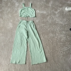 Ljus grönt linne set. Man kan köpa bara en av kläderna för sig själv  - Säljer en ljusgrön croppad linnetopp från H&M med breda axelband och snygg rynkdetalj framtill tillsammans med ett par fladdriga sköna byxor att matcha med. 