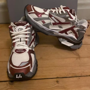 Runner sneakers i vinrött och vitt - Säljer ett par Runner sneakers i vinrött, vitt och grått. Skorna har en sportig design med meshpaneler, kraftig sula och tydlig logga på plösen. Kommer med originalkartong och dustbag.