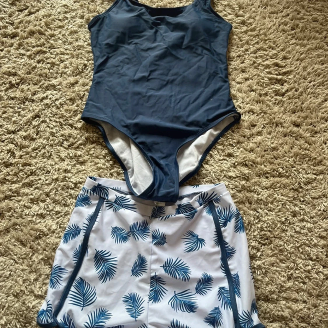 Blå baddräkt och vita badshorts med blått blad-mönster
