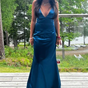 Blå långklänning med v-ringning - Säljer en elegant blå långklänning med djup v-ringning och smala axelband. Klänningen har en figurnära passform upptill och faller snyggt ner mot golvet. Perfekt för bal eller festliga tillfällen. Har sytt upp klänningen så den passar mig som är 156 lång men tror den även kan passa 160 också ☺️