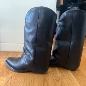 Svarta boots från Pavement - Säljer ett par svarta boots från Pavement i storlek 39. Skorna är tillverkade i skinn och har en klassisk, hög modell med rund tå och platt sula. Perfekta för dig som gillar stilrena och tidlösa skor. ÄKTA skinn, använt fåtal gånger köpt i butik. Köpt för 2900, säljer för 1200 kr, men pris kan diskuteras.