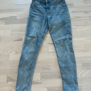 Ljusblå jeansbyxor från Divided - Säljer ett par ljusblå jeansbyxor från Divided i storlek 38. Byxorna har klassisk femficksdesign, normal passform och raka ben i ett stretchigt material. Perfekta till vardags och lätta att matcha med olika toppar.