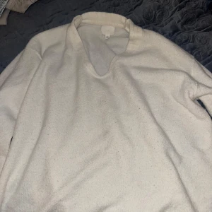 Vit stickad v-ringad tröja - Säljer en enkel och stilren vit stickad tröja med v-ringning. Tröjan har långa ärmar och är perfekt för lager-på-lager under kyligare dagar. Passar till det mesta och är supermjuk och bekväm. Jag har sytt ihop den vid nacken/ axlarna för att den var för stor där innan. Använd några gånger. Bra skick