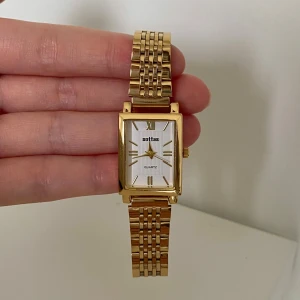 Guldfärgad fyrkantig klocka  - Stilren guldfärgad klocka med fyrkantig vit urtavla.