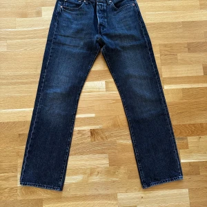 Levi's 501 svarta  jeans - Klassiska Levi's 501 jeans i svart denim med raka ben och femficksmodell. Byxorna har knappgylf och den ikoniska läderpatchen bak i midjan. Perfekta för dig som gillar tidlös stil och vill ha ett par jeans som funkar till allt.