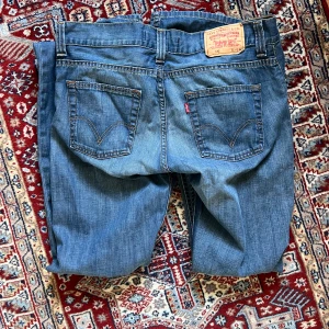 Levi's 512 blå jeans bootcut - Säljer ett par klassiska Levi's 512 jeans i blå denim. Modellen har bootcut-ben, femficksdesign och tydliga sömmar på bakfickorna. Jeansen har normal passform och är tillverkade i bomull. Perfekta för dig som gillar en tidlös look.