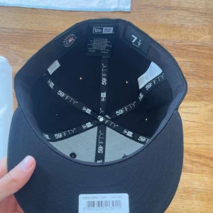 Svart LA 59FIFTY keps från New Era - Säljer en svart New Era 59FIFTY keps med LA-logga broderad i vitt framtill. Klassisk flat peak och stilren design, perfekt för dig som gillar streetwear. Kepsen är i storlek 7 1/2 och kommer med originalpåse från Caphunters.