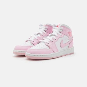 Nike Air Jordan 1 Mid rosa/vit - Snygga Nike Air Jordan 1 Mid sneakers i vitt och ljusrosa skinn med klassisk Jordan-logga på sidan och tungan. Skorna har vita snören (röd följer även med), perforerad tå och en bekväm platt sula. Perfekta för dig som vill sticka ut med en fräsch och trendig look.