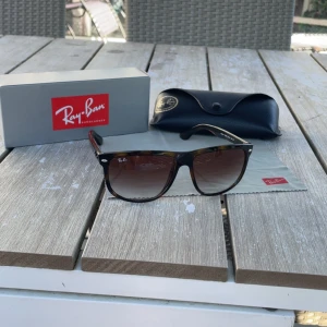 Ray-Ban Boyfriend - Snygga Ray-Ban Boyfriend solglasögon med brunmelerad båge och bruna tonade glas. Klassisk fyrkantig form och diskret logga på linsen. Kommer med originalfodral och putsduk. Perfekta för soliga dagar och ger en cool vibe till din outfit.