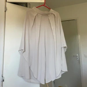 Vida ljusa byxdress med lager-på-lager - Unika vida byxor i ljus färg med lager-på-lager-effekt och snygga veck framtill. Byxorna har hög midja och ett flowigt, nästan kjolliknande fall.