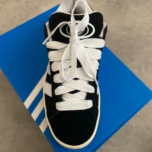 Adidas Campus svartvita sneakers - Svartvita Adidas Campus sneakers med klassiska tre ränder i vitt på sidan, tjocka vita skosnören och gummisula.  Helt nya och oanvända, (beställde fel storlek ) köpta för 1500kr . Kommer även med svarta snöre. 1300kr insklusiv frakt