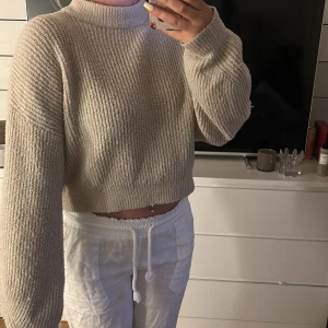 Beige croppad stickad tröja - Supermysig croppad stickad tröja i beige med hög hals och breda ärmar. Storlek s, skulle säga oversized då ja egentligen har M. Perfekt över en sommarklänning. Använd en gång, tvättad 2 gånger