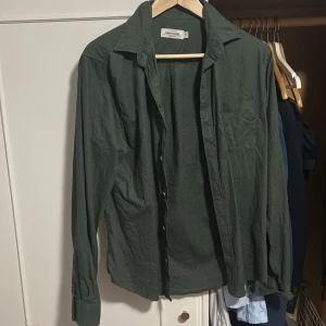 Grön linneskjorta från Dressmann - Stilren grön skjorta från Dressmann i linnemix. Skjortan har klassisk krage, långa ärmar med manschett och knäppning framtill. Perfekt för dig som gillar en avslappnad men ändå snygg look. Passar lika bra till jeans som till chinos.