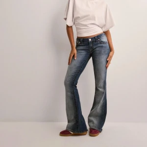 True Religion bootcut jeans blå - Snygga blå bootcut jeans från True Religion med ikoniska bakfickor och röda kontrastsömmar. Jeansen har klassisk femficksdesign, låg midja och är tillverkade i mjukt denim. Perfekta för dig som gillar en avslappnad men trendig look.Dessa är i storlek 27 och använda fåtal gånger,säljs pågrund utav att dem är förstora💕💕