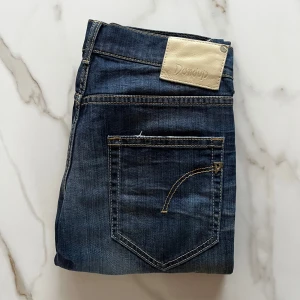 Dondup jeans blå - Snygga blå jeans från Dondup i modellen Dionis. Jeansen har klassisk femficksdesign, gul kontrastsöm och en ljus tvätt. De har rak passform och normal midja. Materialet är mjukt denim i bomull för en skön känsla hela dagen. Inga defekter alls.