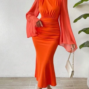 Hell ny Orange långklänning med vida ärmar - Hell ny snygg orange långklänning med markerad midja och vida, transparenta långärmar. Klänningen har rynkade detaljer framtill och en figurnära passform som ger en cool och trendig look. Perfekt för dig som vill sticka ut med färg och stil. Storleken är S/M