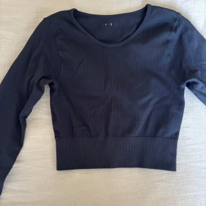 Svart ribbad långärmad tröja - Säljer en svart ribbad långärmad tröja från Stradivarius. Tröjan har en croppad passform, rund halsringning och är tillverkad i mjuk bomullsmix. Perfekt att styla med höga jeans eller kjol för en clean look.