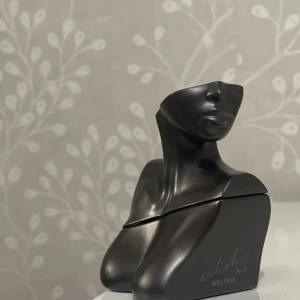 Eilish No. 2 parfym Billie Eilish - Eilish No. 2 av Billie Eilish, en parfym i en unik, svart metallisk flaska formad som en byst. Flaskan rymmer 50 ml och har en modern, konstnärlig design med matta och blanka ytor. Perfekt för dig som gillar snygga och annorlunda parfymflaskor.