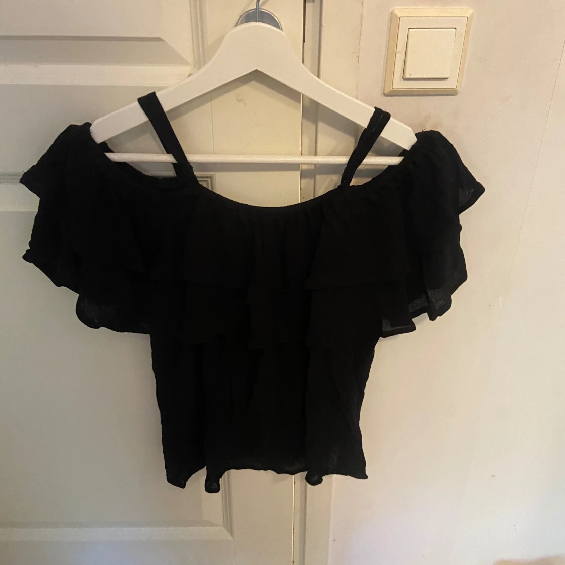 Svart volangig blus med axelband