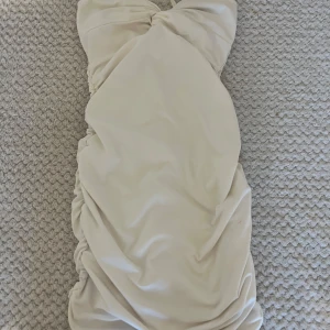 Vit elegant klänning  - Supersnygg vit kort klänning med smala axelband och twistad omlottdetalj vid bysten. Klänningen har rynk längs sidorna som ger en tight och figurnära passform. Perfekt för dig som gillar en stilren och trendig look. Den är jätte stretchig så passar alla pris kan diskuteras🤍