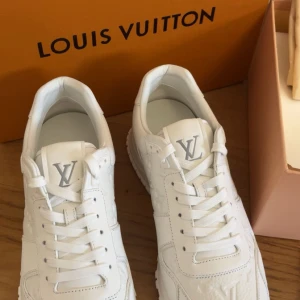 Vita Louis Vuitton sneakers - Exklusiva vita sneakers från Louis Vuitton med LV-logga på plösen och präglade monogramdetaljer på sidorna. Skorna har snörning, rund tå och en chunky platt sula. Tillverkade i skinn för en lyxig känsla och stilren look. Oanvända. priset kan diskuteras!