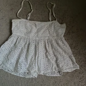 Sommar topp - Supersöt vit linnetopp med tunna axelband och broderade hålmönster. Toppen har en luftig och flowy passform med volangkant nedtill. Pris kan diskuteras 